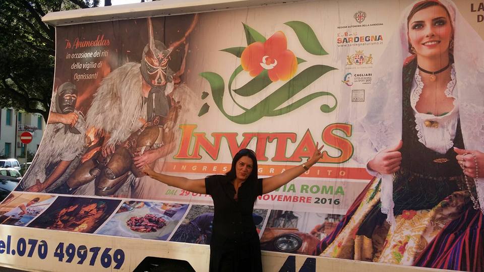 Alessia Littarru fiera davanti ad un cartellone pubblicitario per la promozione dell'evento InvitaS  - eventi enogastronomici in Sardegna